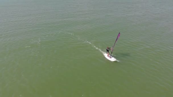 Un hombre flota en una tabla de surf con una vela. Disparo aéreo — Vídeos de Stock