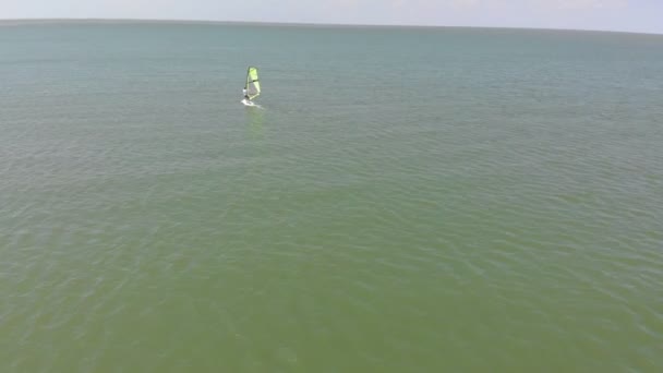 Un hombre flota en una tabla de surf con una vela. Disparo aéreo — Vídeos de Stock