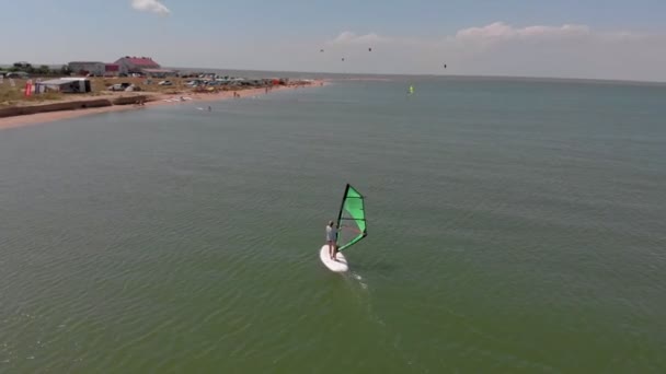 A man floats on a surf board with a sail. Aerial shot — Stock Video