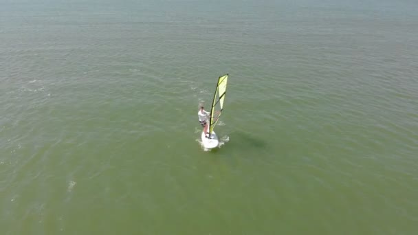 Un hombre flota en una tabla de surf con una vela. Disparo aéreo — Vídeos de Stock