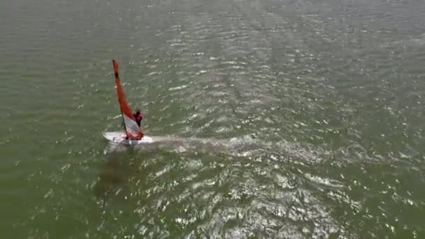 Человек плавает на доске для серфинга с парусом. Воздушный удар — стоковое видео