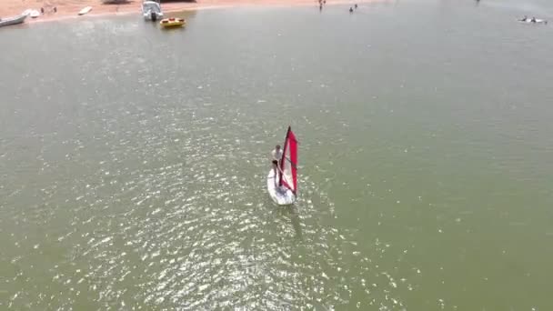 Un homme flotte sur une planche de surf avec une voile. Plan aérien — Video