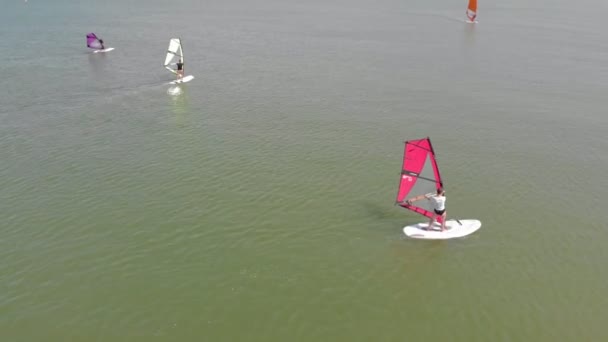 Un homme flotte sur une planche de surf avec une voile. Plan aérien — Video