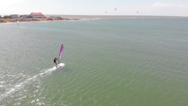 Un homme flotte sur une planche de surf avec une voile. Plan aérien — Video