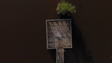 Genç bir kadın nehir kıyısında bir tablet kullanıyor. Havadan çekim