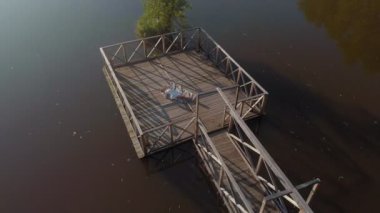 Genç bir kadın nehir kıyısında bir tablet kullanıyor. Havadan çekim