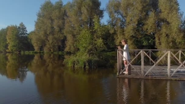 Młoda kobieta używa tabletu przez rzekę. Strzał z lotu ptaka — Wideo stockowe