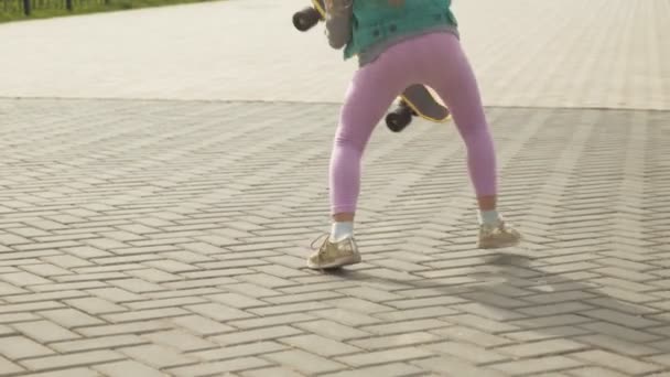 Egy kislány lovagol egy sárga gördeszka — Stock videók
