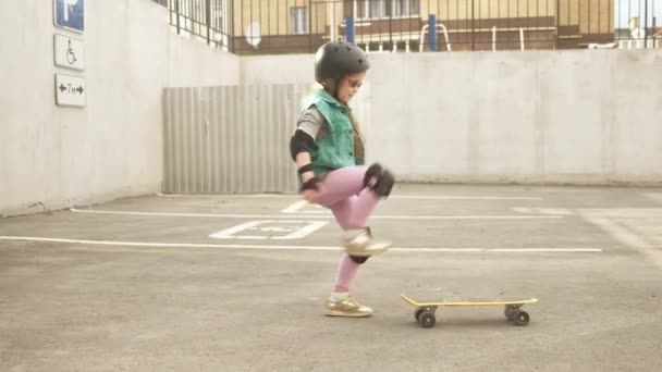 Uma menina cavalga em um skate amarelo — Vídeo de Stock