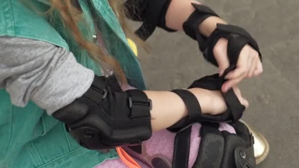 Little girl dresses protection: helmet, knee pads and elbow pads. Sunset — Stock Video