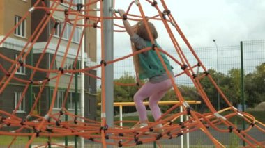 Bir çocuk açık bir oyun alanında bir ip yatay bar tırmanıyor