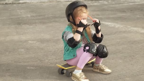 Little girl dresses protection: helmet, knee pads and elbow pads. Sunset — Stock Video