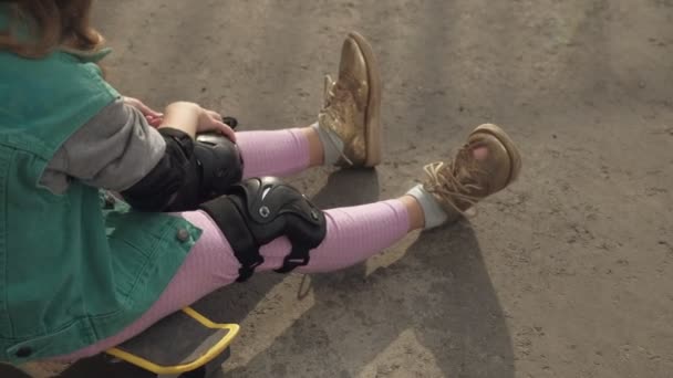 Gadis kecil berpakaian perlindungan: helm, bantalan lutut dan bantalan siku. Matahari terbenam — Stok Video
