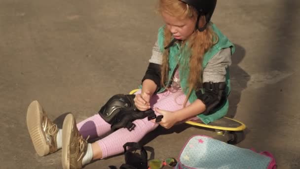 Little girl dresses protection: helmet, knee pads and elbow pads. Sunset — Stock Video