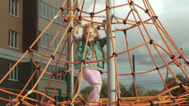 Uma criança sobe uma barra horizontal de corda em um parque infantil ao ar livre — Vídeo de Stock