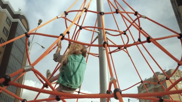 Un niño sube a una barra horizontal de cuerda en un patio al aire libre — Vídeos de Stock