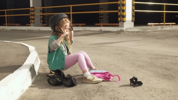 Little girl dresses protection: helmet, knee pads and elbow pads. Sunset — Stock Video