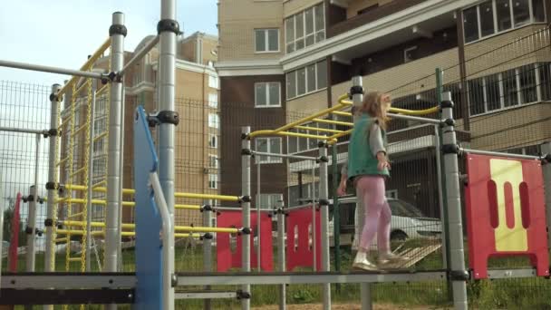 한 어린 소녀가 야외 운동장에서 놀고 있다. 일몰 — 비디오