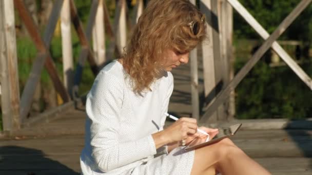 Mujer está utilizando una tableta de ordenador al aire libre . — Vídeos de Stock