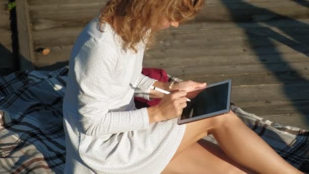 Mujer está utilizando una tableta de ordenador al aire libre . — Vídeos de Stock