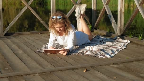 Mulher está usando um tablet de computador ao ar livre . — Vídeo de Stock