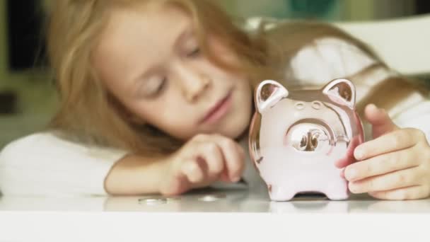 Meisje kleuter zet geld in een Piggy Bank Pink Pig — Stockvideo