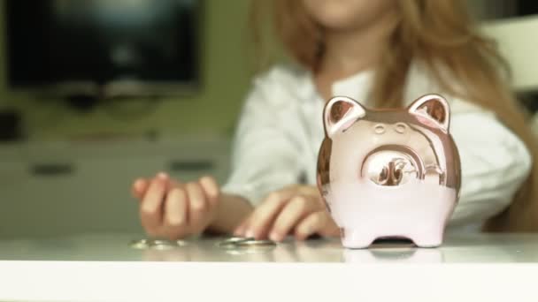 Lány preschooler tesz pénzt egy malacka bank rózsaszín disznó — Stock videók