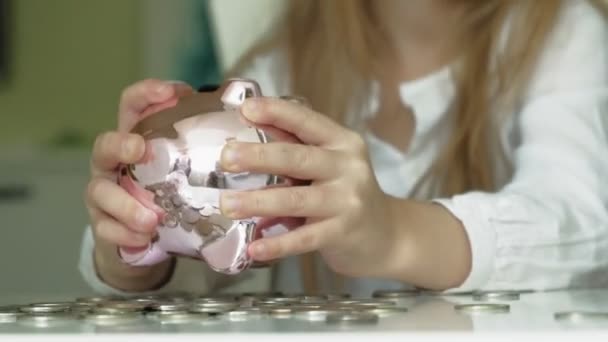 Girl preschooler puts money in a piggy bank pink pig — Stock Video