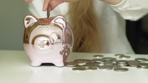 여자 미취학 아동은 돼지 저금통 핑크 돼지에 돈을 넣습니다 — 비디오