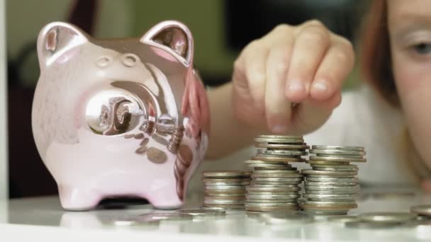 女の子の未就学児は、貯金箱ピンクの豚にお金を入れます — ストック動画