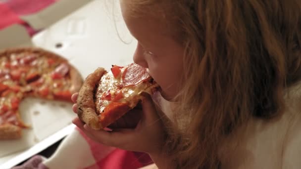 Vorschulmädchen isst Pizza, während sie auf dem Fußboden im Zimmer sitzt — Stockvideo
