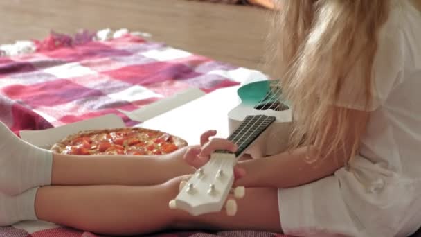 Niña preescolar comiendo pizza mientras está sentada en el piso en la habitación — Vídeos de Stock