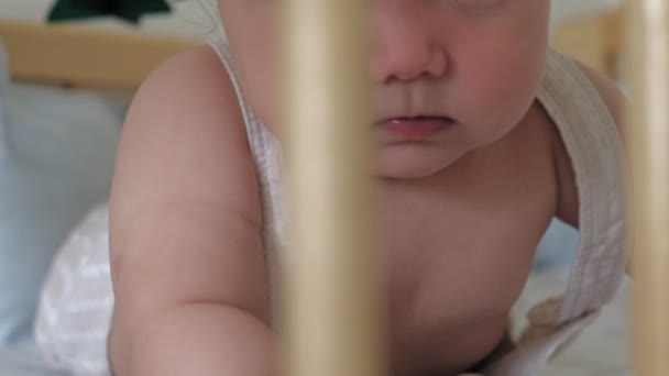 幼児の女の子は、ベビーベッドに横たわって彼女の頭を維持することを学びます. — ストック動画