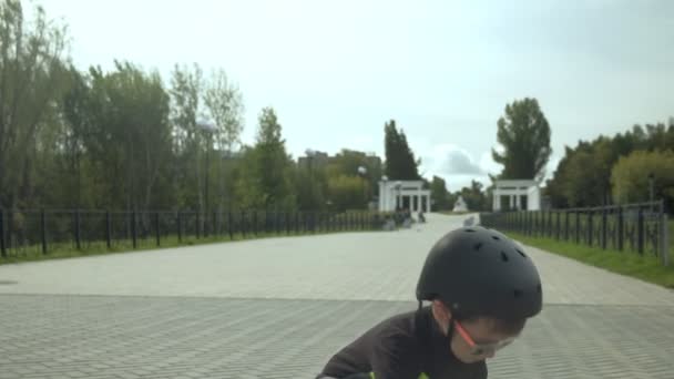 Um menino pré-escolar com um capacete de proteção monta um skate em Park. Verão — Vídeo de Stock