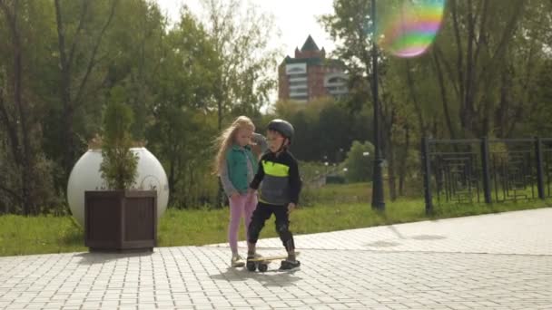 一个戴着防护头盔的学龄前儿童在公园里骑车。夏天 — 图库视频影像