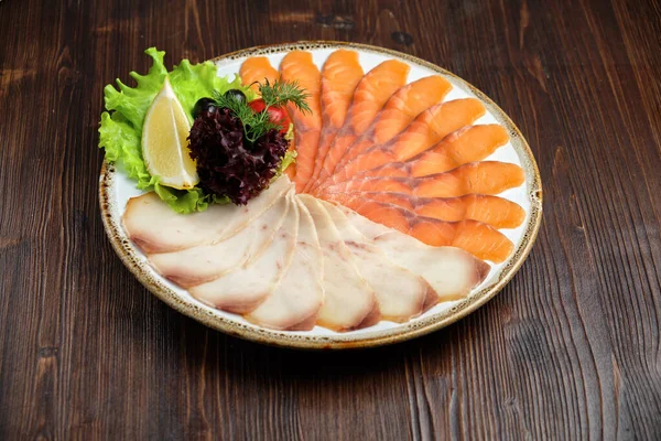 Ikan putih dan merah diiris dalam irisan tipis pada latar belakang kayu cokelat. menu restoran Stok Gambar Bebas Royalti