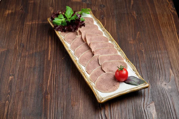 Rundvlees tong gesneden in dunne plakjes op een bord op een bruine rustieke achtergrond. Restaurant menu — Stockfoto