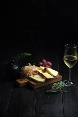 Bir bardak soğuk beyaz şarap ve ahşap üzerinde peynirli atıştırmalık. yemek menüsü