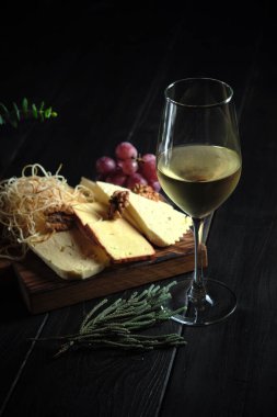Bir bardak soğuk beyaz şarap ve ahşap üzerinde peynirli atıştırmalık. yemek menüsü