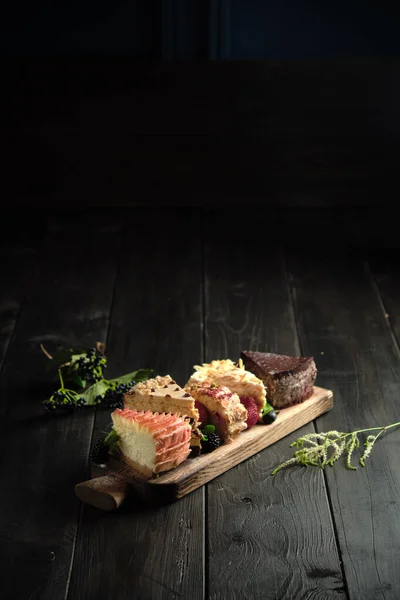 Różne kawałki ciasta na drewnianej desce. menu cateringowe — Zdjęcie stockowe