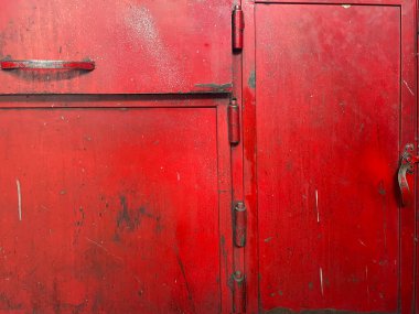 Üzerinde çizikler, kabuk soyulmuş boya ve kırsal doku olan eski kırmızı metal dolap kapısı. Grunge tasarımı için endüstriyel vintage arka plan, atölye atmosferi, eski çelik yüzey ve inşaat ayrıntıları.