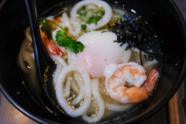 Udon 'un deniz ürünleri mürekkep balığı, karides ve yumurtayla yakın çekimi. Japon mutfağı. Yiyecek ve içecek konsepti. Gıda arkaplanı.