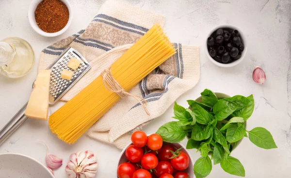 Beyaz arka planda spagetti pişirmek için ham malzemeler. Makarna, domates, sarımsak, fesleğen, parmesan ve zeytin. en üstteki görünüm