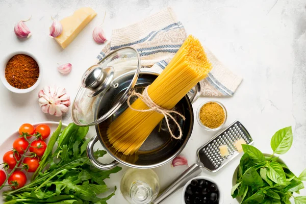 Beyaz arka planda spagetti pişirmek için ham malzemeler. Makarna, domates, sarımsak, bazel, parmesan ve zeytin. en üstteki görünüm