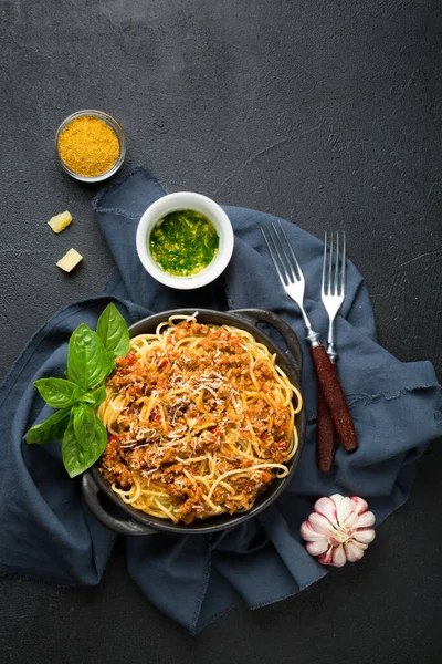 Bolonez soslu spagetti, siyah arka planda zeytin ve baharatlar. Üst görünüm