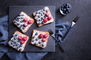 Siyah arka planda taze yaban mersinli ve ahududulu lezzetli bir tatlı. en üstteki görünüm