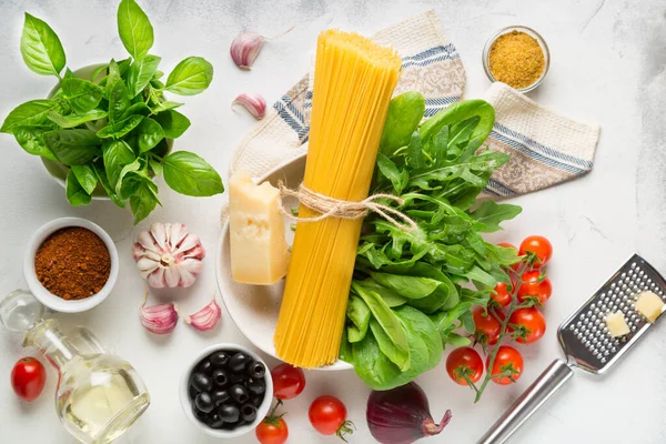 Beyaz arka planda spagetti pişirmek için ham malzemeler. Makarna, domates, sarımsak, fesleğen, parmesan ve zeytin. en üstteki görünüm