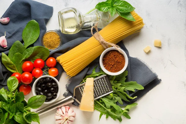 Beyaz arka planda spagetti pişirmek için ham malzemeler. Makarna, domates, sarımsak, fesleğen, parmesan ve zeytin. en üstteki görünüm