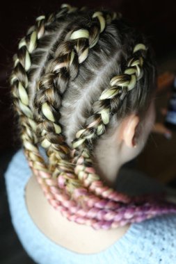 a hairstyle made of thick braid with a kanekalon for a girl, five braids with an interlacing of artificial material. boxing braids, trends in hairstyles clipart