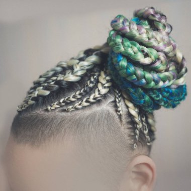 kadın A kadın beyaz bir arka planda, bir saç kesimi ile cornrows örgülü saçları dokunmuş bir kuyruk, yapay malzeme içine sıkı örgüler